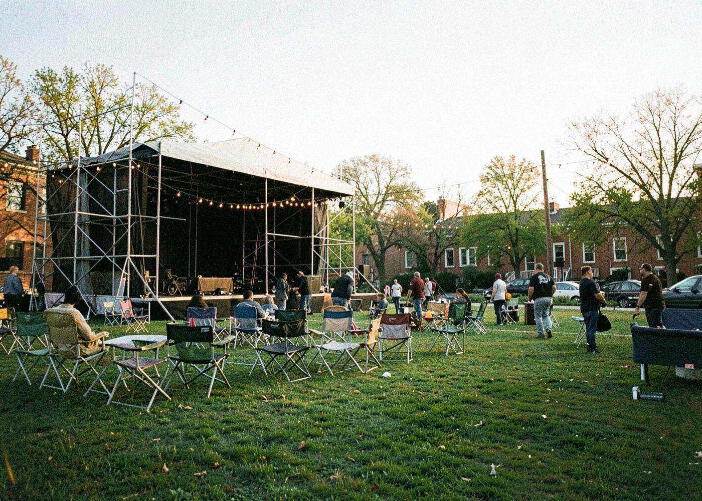 A stage being set up on a college green at dusk