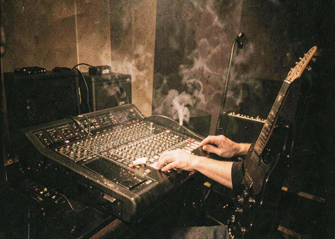 Hands working a mixing console in a dim studio